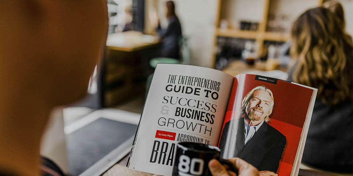 A man is reading an article in a magazine about personal branding.